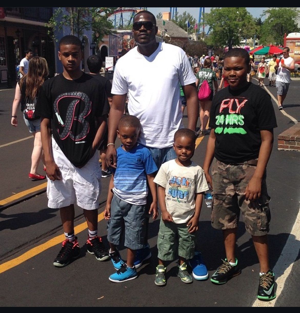 Group of five people posing on a sunny day at an amusement park.