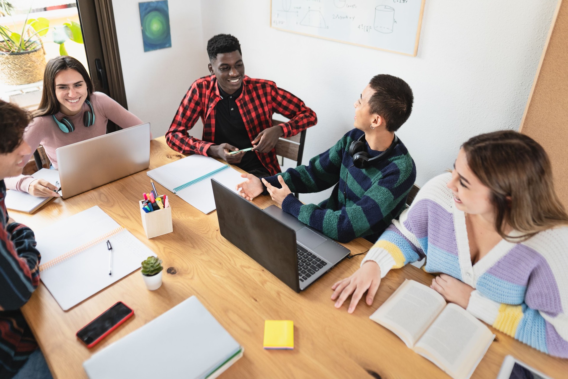 Young multiracial students reading books and using laptop in classroom while studying together -   School education concept - Focus on Asian guy