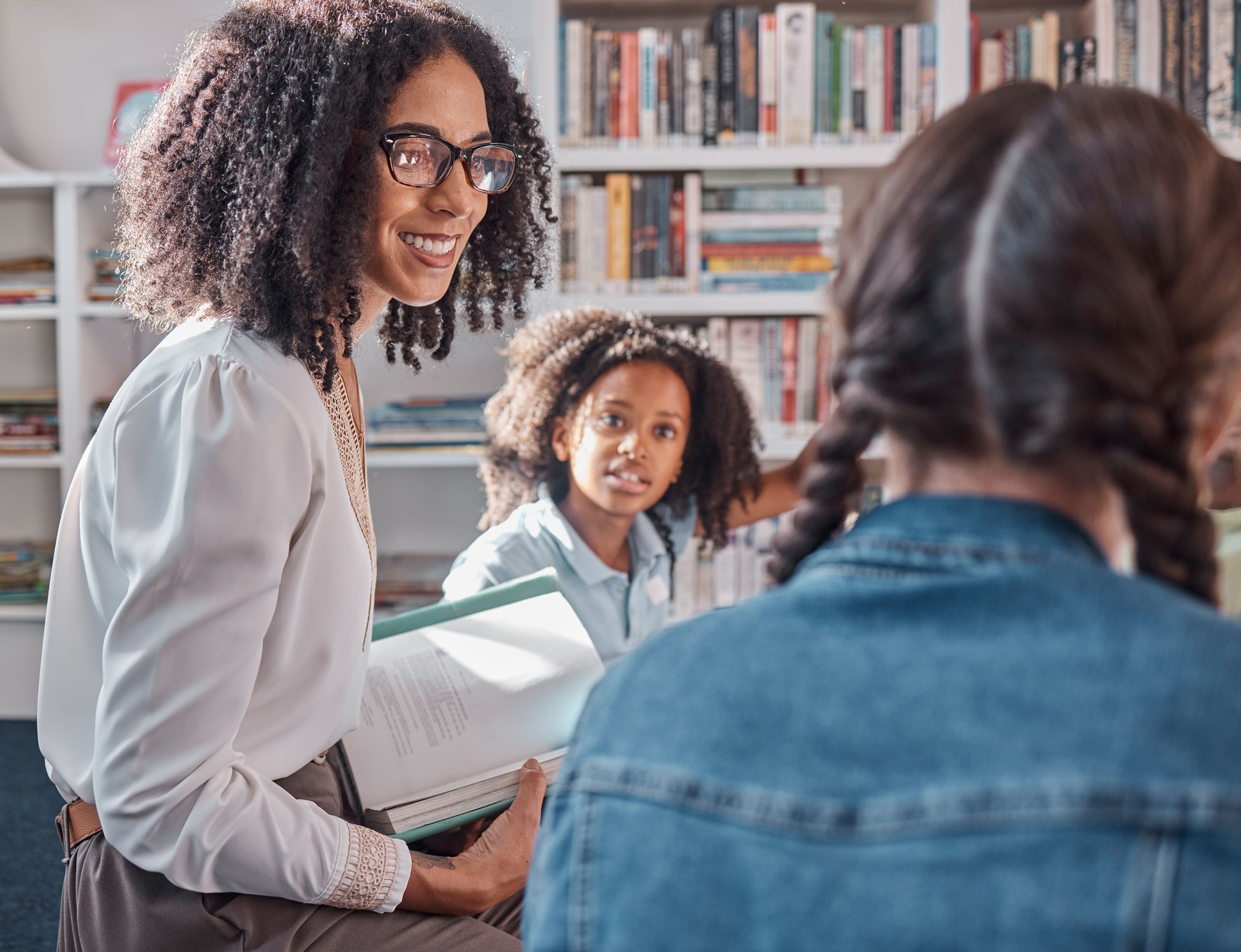 Teacher, storytelling or children in a library for learning development, reading skills or growth. Happy smile, kids or students listening to a black woman asking for feedback on fun books at school